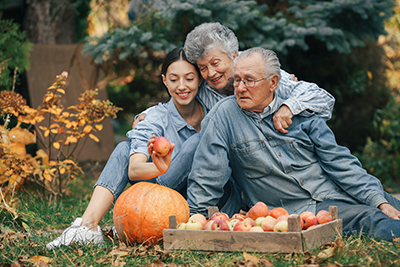 Family Sitting In A Garden With Apples And Pumpkin